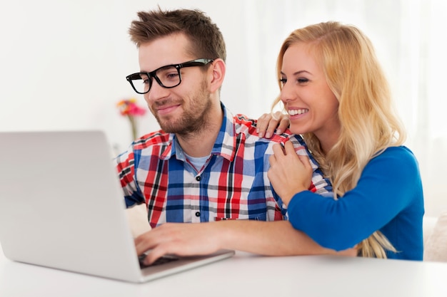 Pareja feliz mirando algo en la computadora portátil