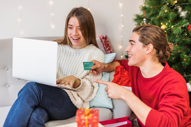 Pareja feliz mirando la pantalla del portátil en el sofá