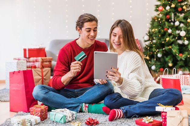 Pareja feliz mirando tablet en el piso