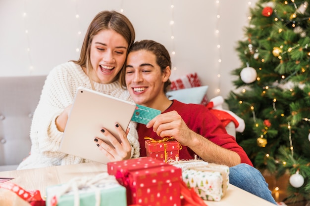 Pareja feliz mirando tablet con tarjeta de crédito