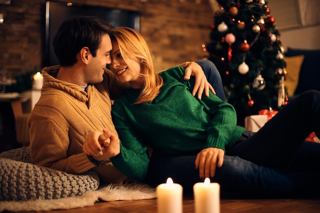 Pareja feliz mostrando afecto mientras se relaja en la víspera de Navidad en casa