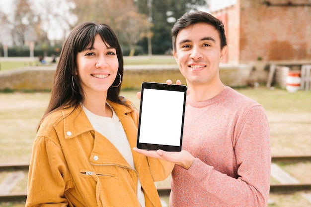 Foto gratuita pareja feliz mostrando tableta en la calle