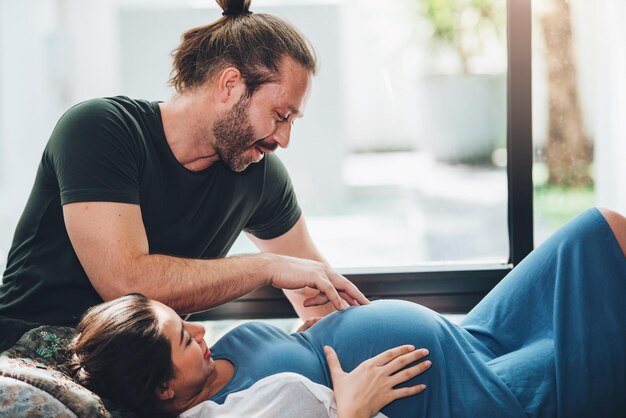 Pareja feliz mujer embarazada y esposo se quedan en casa en la sala de estar Pareja feliz cuidando juntos