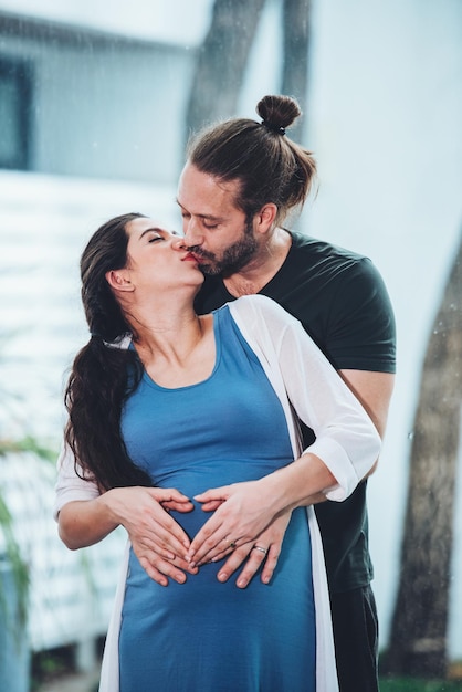 Pareja feliz mujer embarazada y esposo se quedan en casa en la sala de estar Pareja feliz cuidando juntos