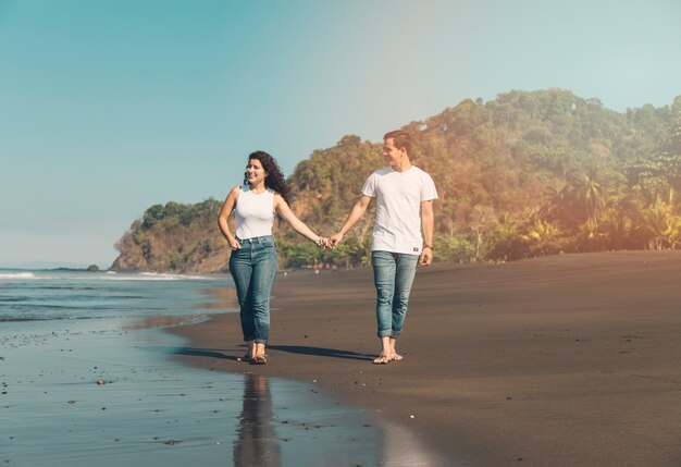 Pareja feliz paseando por la orilla del mar