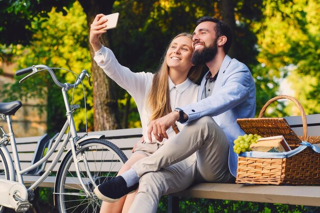 Pareja feliz en un picnic hace selfie.