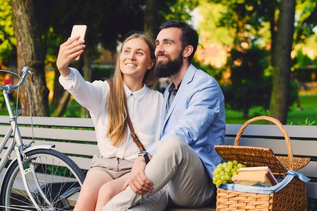 Pareja feliz en un picnic hace selfie.