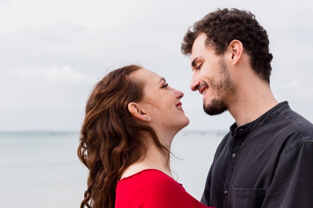 Pareja feliz de pie en la orilla del mar