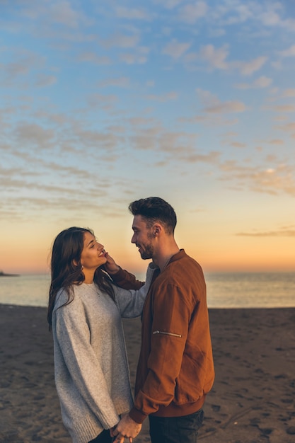 Foto gratuita pareja feliz de pie en la orilla del mar