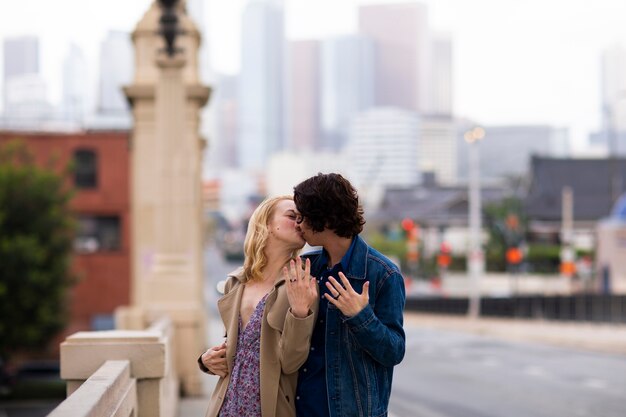 Pareja feliz posando al aire libre en la ciudad con anillo de compromiso