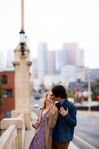 Pareja feliz posando al aire libre en la ciudad con anillo de compromiso