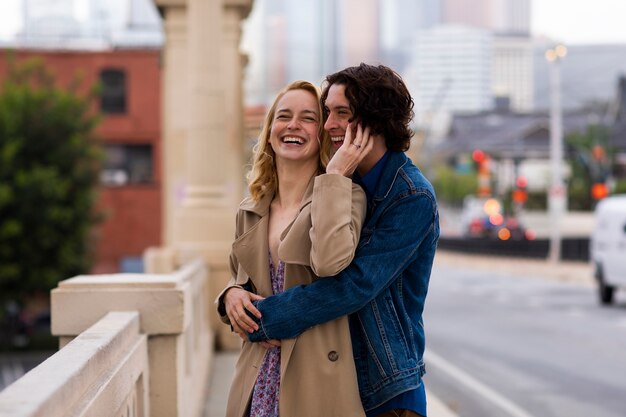 Pareja feliz posando al aire libre en la ciudad con anillo de compromiso