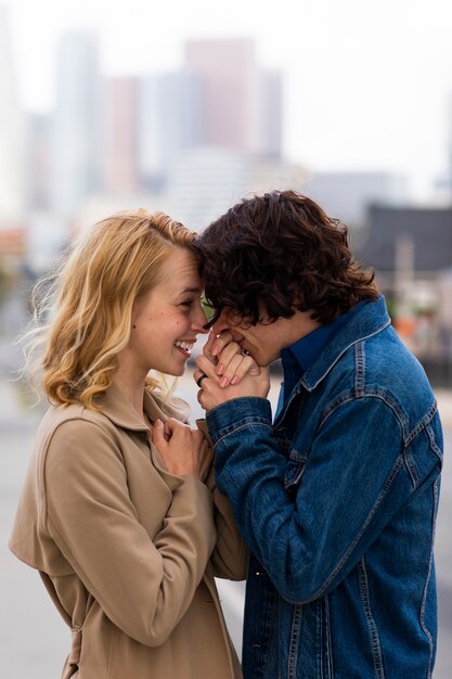 Pareja feliz posando al aire libre en la ciudad con anillo de compromiso