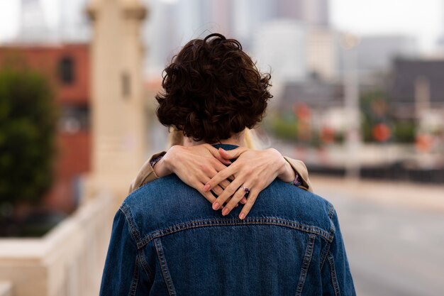 Pareja feliz posando al aire libre en la ciudad con anillo de compromiso