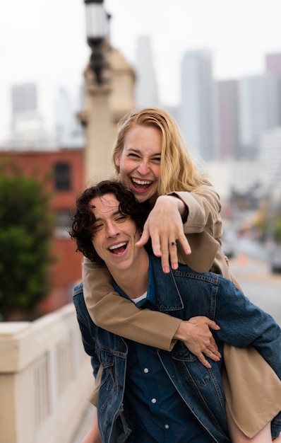 Pareja feliz posando al aire libre en la ciudad con anillo de compromiso