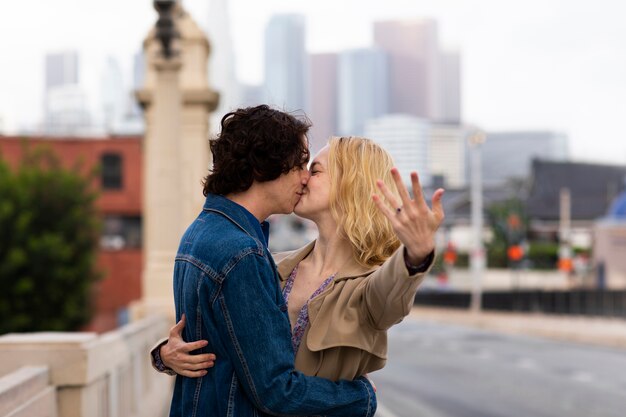 Pareja feliz posando al aire libre en la ciudad con anillo de compromiso