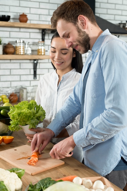 Pareja feliz preparando la comida juntos en la cocina