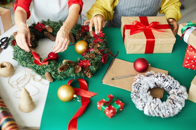 Pareja feliz preparando guirnalda y regalos de navidad