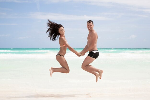 Pareja feliz saltando en la playa