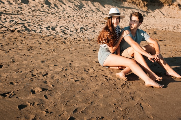 Pareja feliz sentada en la arena