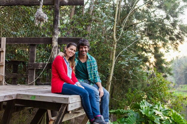 Pareja feliz sentada en tablones de madera