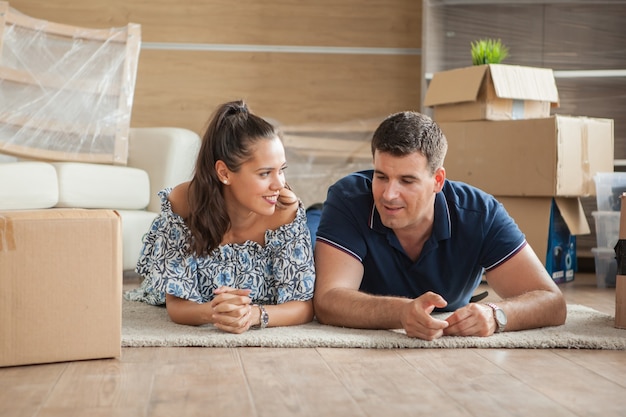 Pareja feliz en el suelo de su nueva casa. Hipoteca y familia