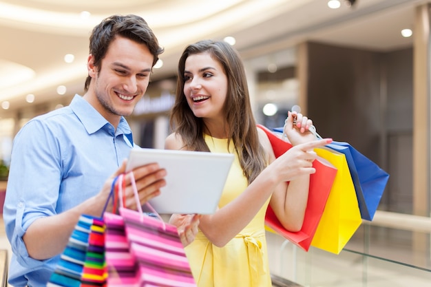 Pareja feliz con tableta digital durante las compras