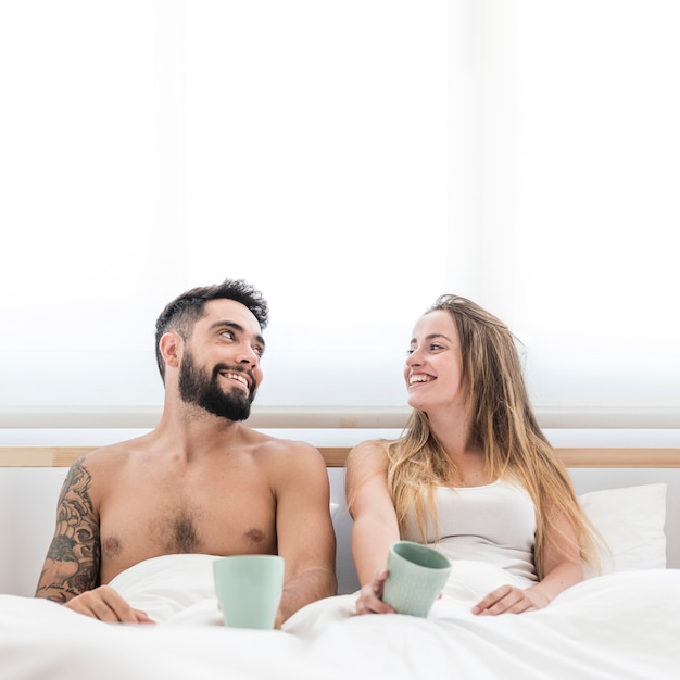 Pareja feliz con taza de café mirando el uno al otro