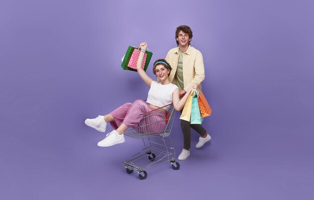 Una pareja feliz tirada en un carrito de compras y una mano sosteniendo una bolsa de compras corriendo al lado de la tienda