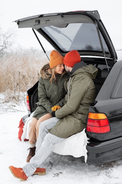 Pareja feliz de tiro completo en el baúl del auto