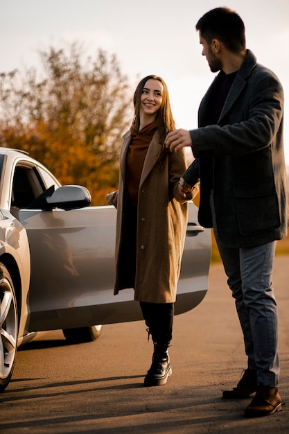 Pareja feliz de tiro completo con coche