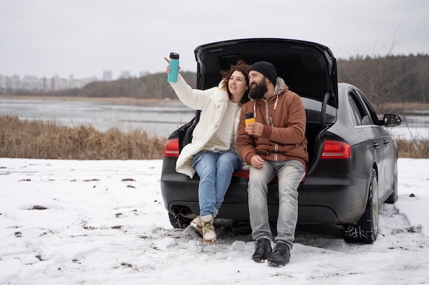 Foto gratuita pareja feliz de tiro completo con coche