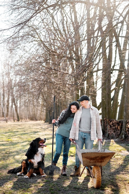 Foto gratuita pareja feliz de tiro completo con perro en la naturaleza