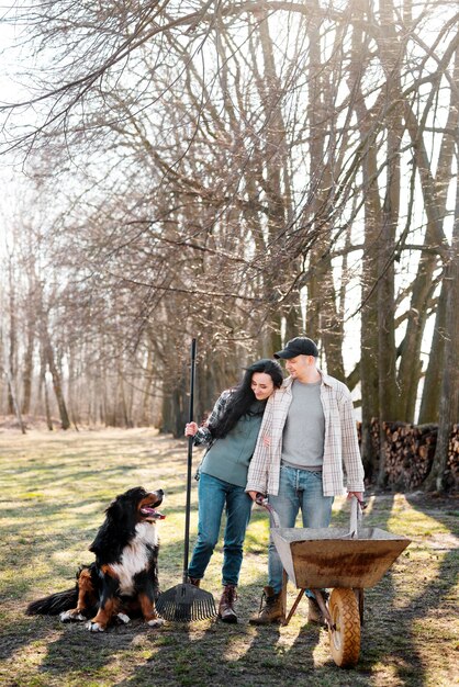 Pareja feliz de tiro completo con perro en la naturaleza