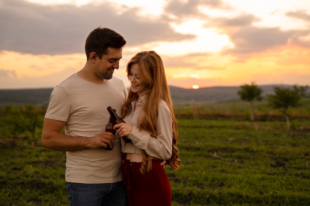 Pareja feliz de tiro medio con botellas