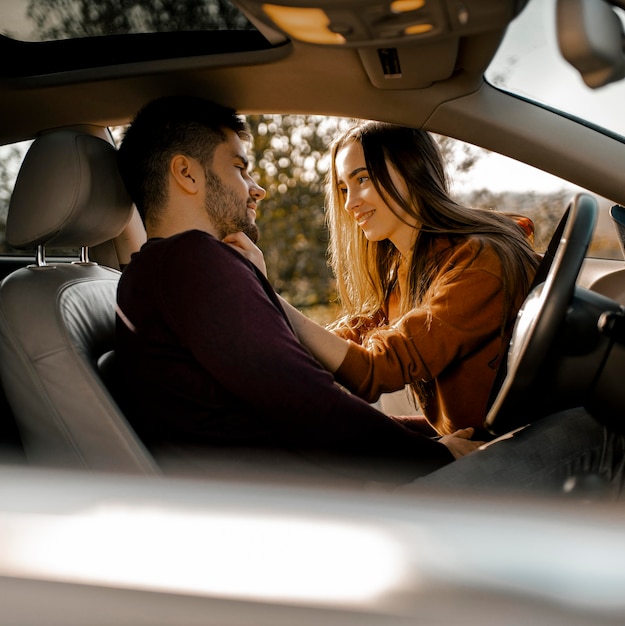 Pareja feliz de tiro medio en coche