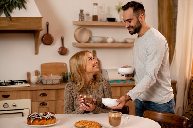 Pareja feliz de tiro medio en la cocina