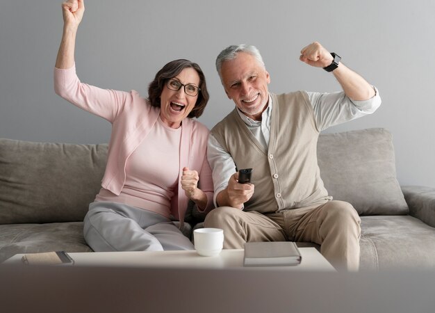 Pareja feliz de tiro medio con control remoto