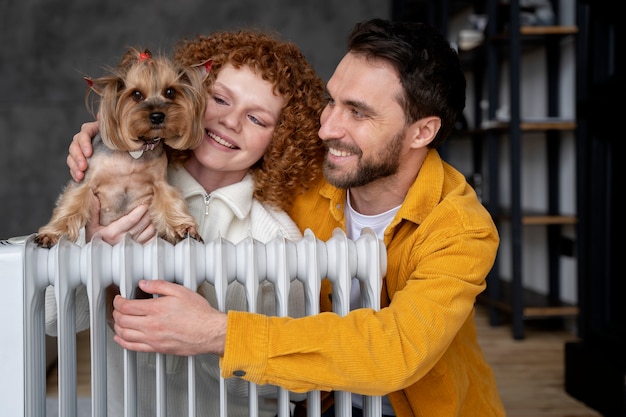 Pareja feliz de tiro medio y perro con calentador