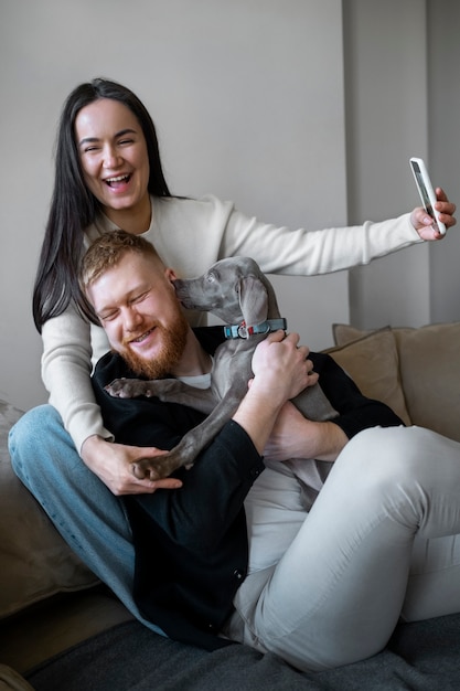 Pareja feliz de tiro medio tomando selfie en casa