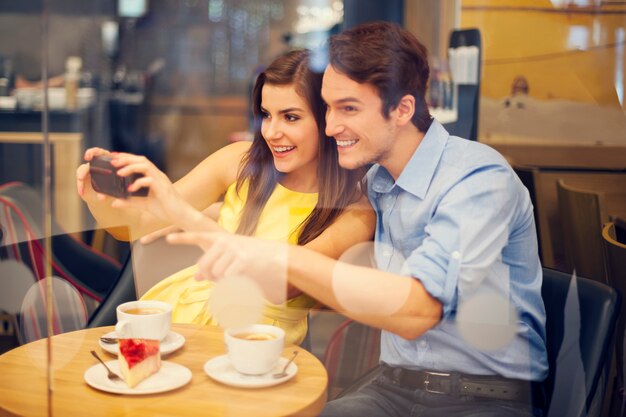 Pareja feliz tomando fotos en el café