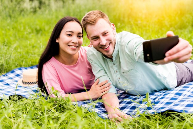 Pareja feliz tomando selfie acostado