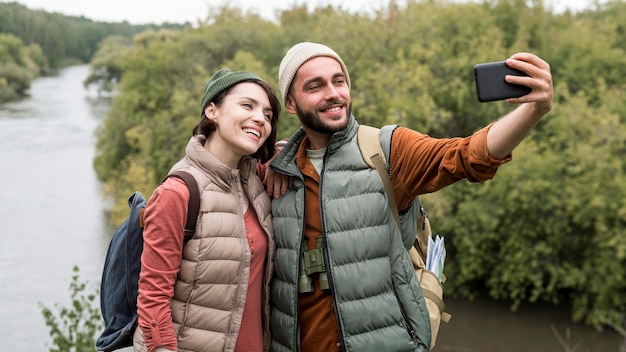 Pareja feliz tomando un selfie con smartphone en la naturaleza