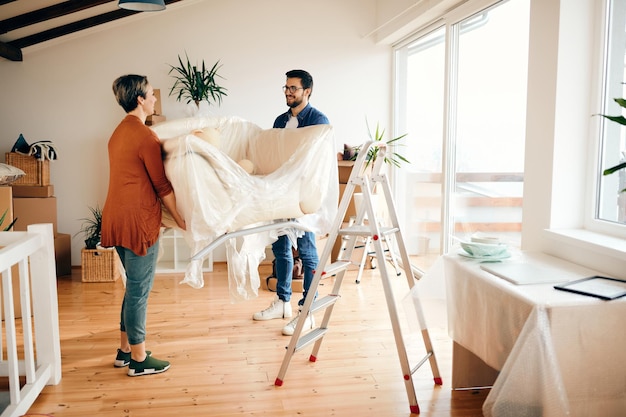 Pareja feliz trayendo un sofá en su nuevo apartamento