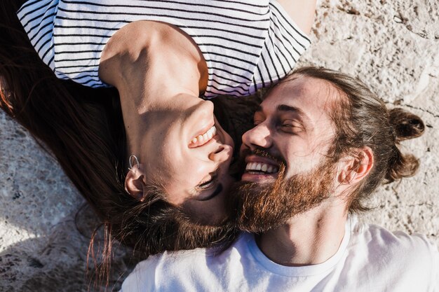 Pareja feliz tumbada en rocas por el mar