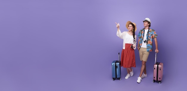 Pareja feliz turista mano apuntando a copiar espacio con equipaje que va a viajar de vacaciones