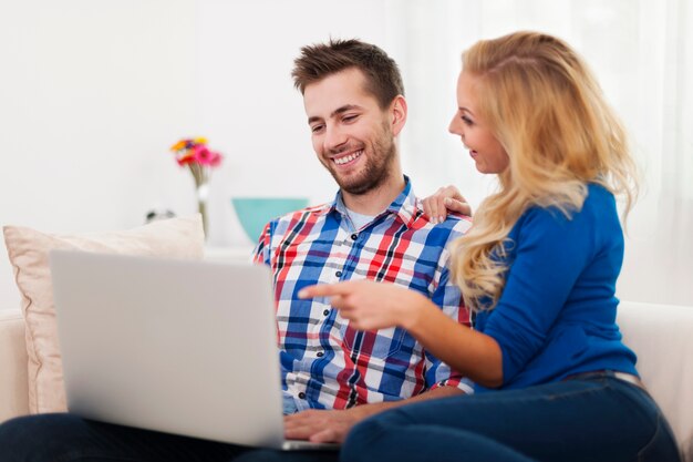 Pareja feliz usando computadora en casa