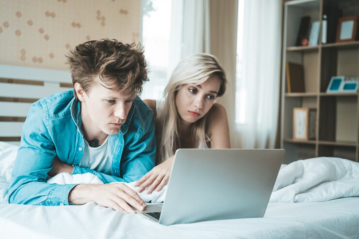 Foto gratuito pareja feliz usando la computadora portátil en la cama