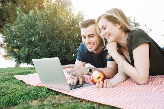 Foto gratuita pareja feliz usando laptop en picnic