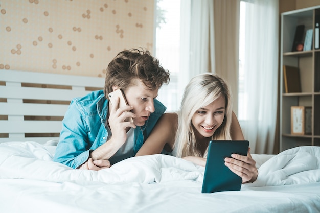 Pareja feliz usando tableta en la cama